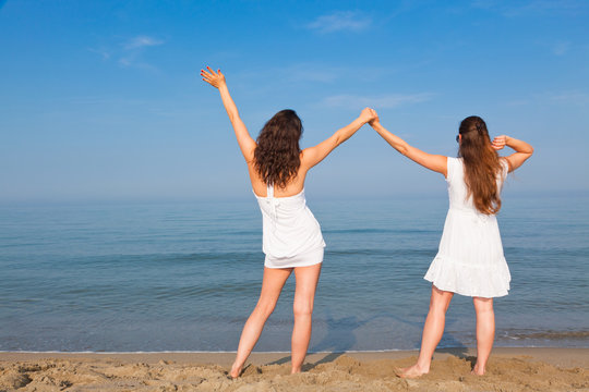 Two Young Women with Arms Outstretched on Seaside