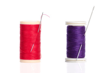 Two red and purple thread bobbin and needle