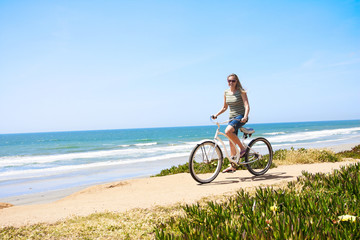 Obraz premium Woman on a Bicycle Ride along the beach