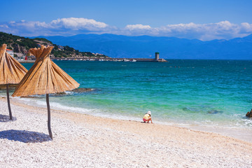 straw gamps lined up on the shingly beach in Baska, Croatia