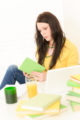 Young student girl reading book at home