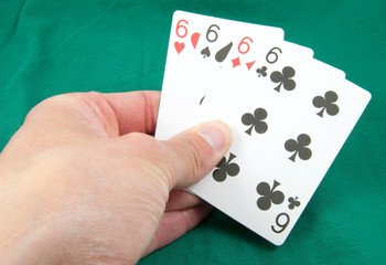 four sixes in card hand on green card table