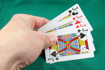 four jacks in card hand on green card table