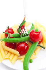 tomatoes, peas, pasta and fork on a plate isolated on white