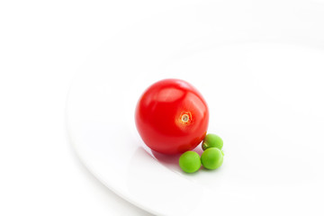 tomato and peas on a plate isolated on white