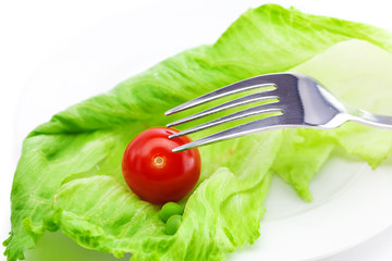 tomato and lettuce with a fork on a plate isolated on white
