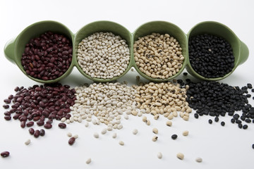 Assorted mixed dried beans spilling in green ceramic dish