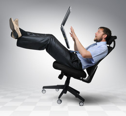 Businessman with laptop falls from an office chair, concept