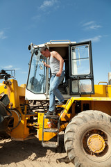 Мужчина вылезает из автопогрузчика.