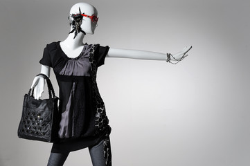 Fashion clothes on a mannequin holding handbag posing on gray