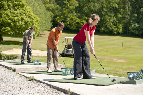 golfers inline at the driving range