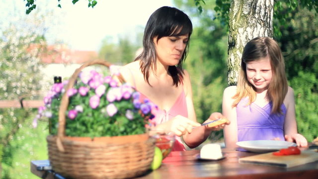 Mother with doughter preparing sandwich in garden, dolly shot