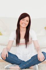 Attractive red-haired woman posing while sitting on a carpet