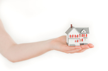 Arm holding a miniature house on a white background