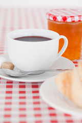 Continental breakfast with croissant, jam and coffee on a tablec