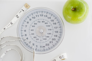 Top view of a green apple along with a tape measure and a weigh-