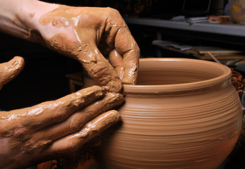 hands of a potter, creating an earthen jar on the circle