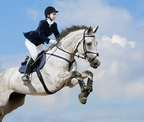 Equestrian jumper - young girl jumping with dapple-grey horse
