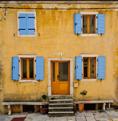 Fototapeta na wymiar Front of an old house with blue shutters and yellow wall