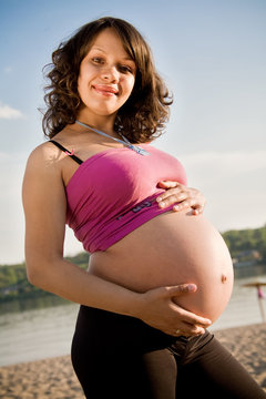 Beautiful young pregnant woman on summer beach