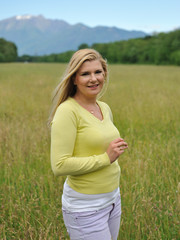 Pretty healthy summer woman outdoors on green field in Alps enjo
