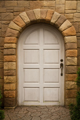 Fototapeta na wymiar Wooden Arched Door on a Stone Wall