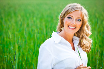 Fototapeta na wymiar Blond woman portrait outdoor on green field