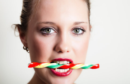 Young Woman Holding Candy In Her Teeth