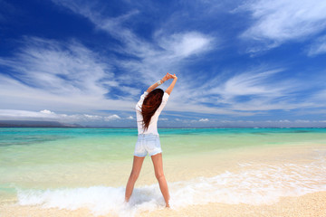 水納島の波打ち際でストレッチをしている後姿の女性