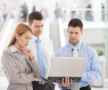Young businesspeople looking at laptop screen