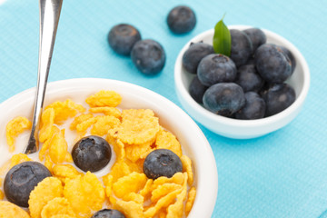 bowl of cornflakes with milk and blueberries
