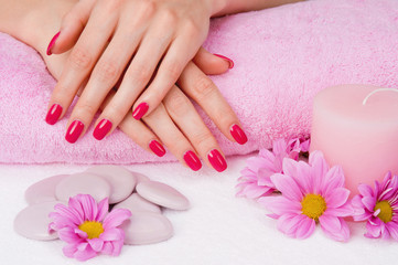 Obraz na płótnie Canvas Spa manicure z różowymi kwiatami, kamieniami i świeca