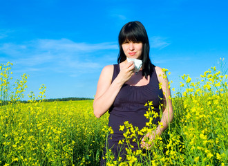 Allergy / Young woman blowing her nose on the rapeseed field