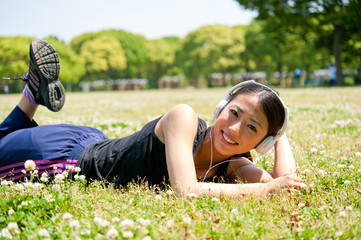 beautiful asian woman listening music in the park