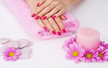 Spa manicure treatment with pink flowers, stones and candle