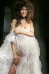 Fototapeta premium Wild styled lady indoors in the dark stony dungeon. Vertical pho