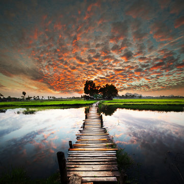 Fototapeta Fototapeta Drewniany most przez rzekę podczas kolorowego zachodu słońca do pokoju