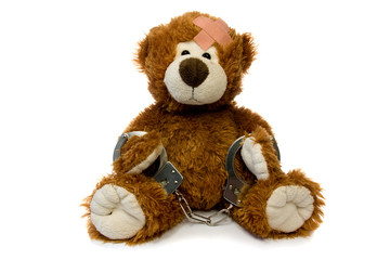 injured and handcuffed Teddy bear on white background.