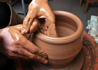 hands of a potter, creating an earthen jar on the circle