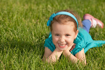 Cheerful smiling little girl on the green grass