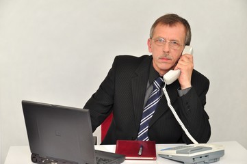 Meżczyzna za biurkiem rozmawia przez telefon
