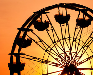 Silhouette of ferris wheel at sunset at county fair.