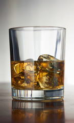 Whiskey with ice cubes on abstract