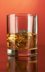 Whiskey with ice cubes on red