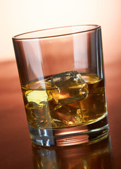 Whiskey with ice cubes on red