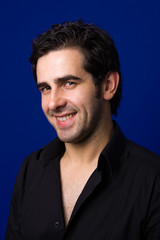 smiling handsome young man standing on blue background