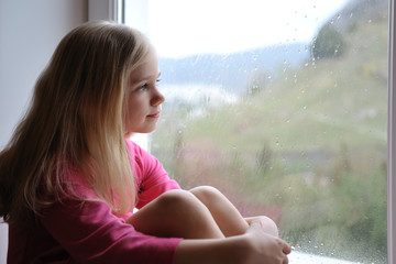 Девочка смотрит в окно.
