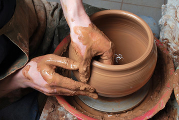 hands of a potter, creating an earthen jar on the circle