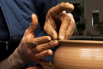 hands of a potter, creating an earthen jar on the circle