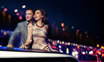 Elegant couple traveling a limousine at night - obrazy, fototapety, plakaty